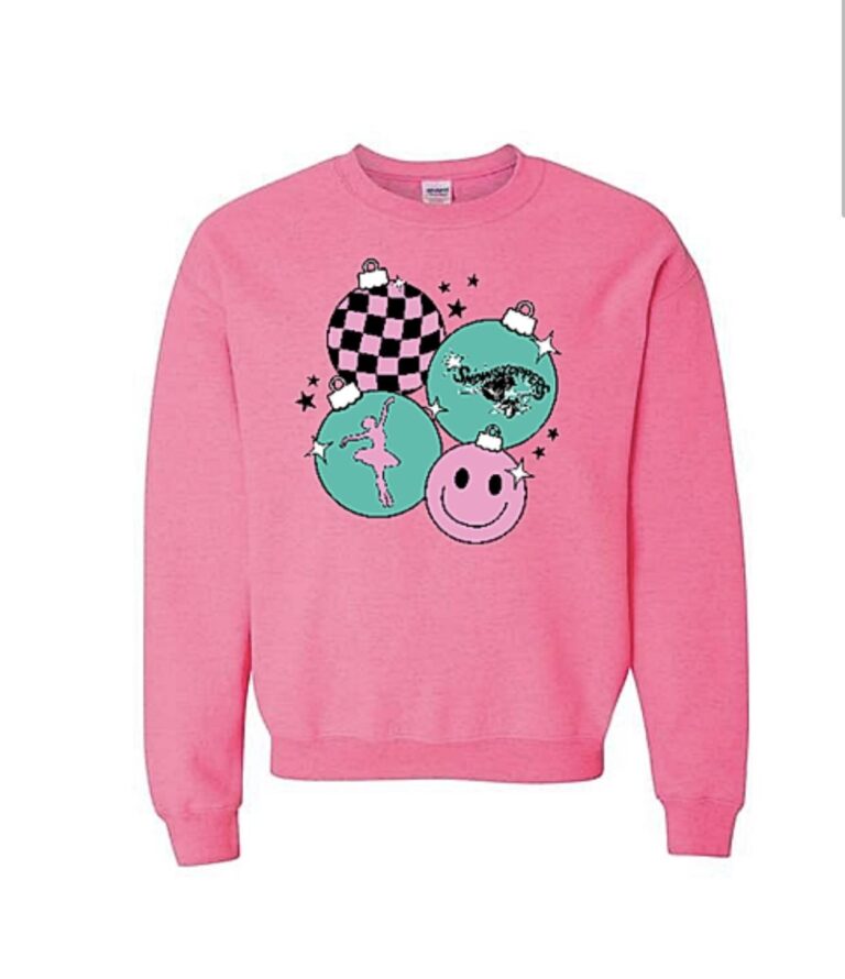 A pink sweatshirt featuring four teal and pink Christmas ornaments with unique designs—like a ballerina inspired by dance classes Stillwater—plus checkerboard, landscape, and smiling face patterns, all surrounded by small black stars. -Showstoppers Dance Studio